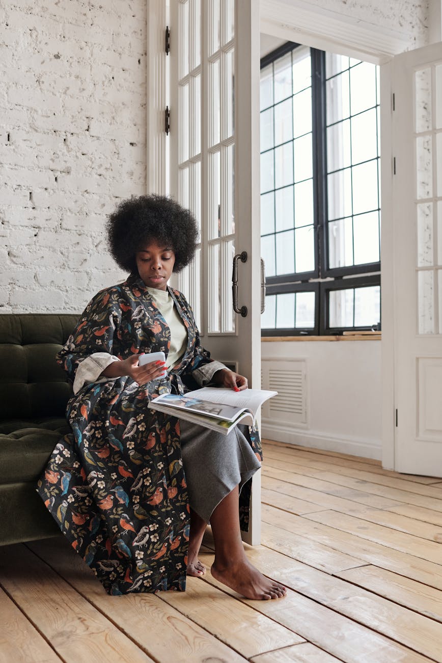 woman sitting on a sofa with a magazine and a smartphone