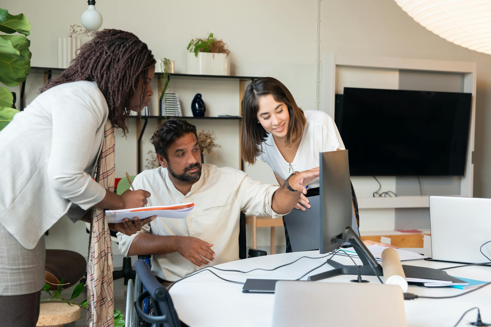 photograph of a man showing something on the monitor to his coworkers